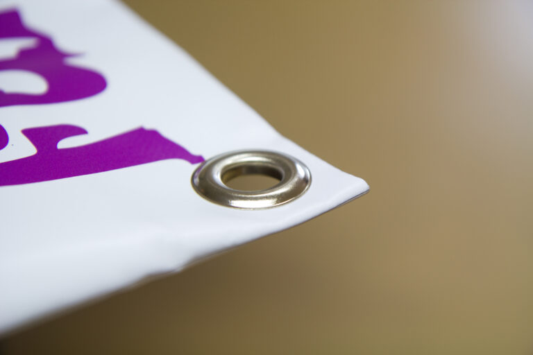 Gros plan d'un œillet posé dans un angle de banderole - Next publicité Vosges